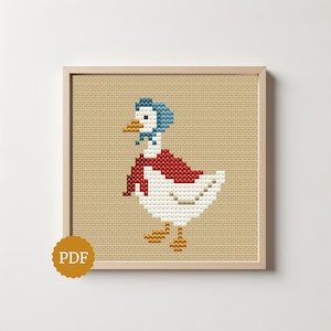 May include: A cross-stitch pattern featuring a white goose wearing a blue bonnet and a red scarf. The goose has an orange beak and orange feet, set against a tan Aida cloth background. A circular gold badge with the text PDF is in the corner.