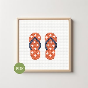 May include: Cross-stitch artwork of two orange flip-flops with white cross accents and navy blue straps. The artwork is framed in a light wood frame and set against a white background. A green PDF sticker is in the lower left corner.