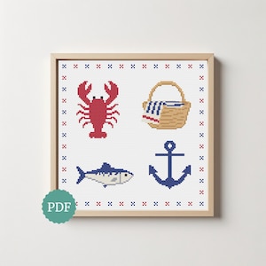 Könnte beinhalten: Ein gerahmtes Kreuzstichmuster mit einem roten Hummer, einem beigen Picknickkorb mit blau-weiß gestreiftem Tuch, einem blauen Fisch und einem blauen Anker. Das Design ist von einem wiederkehrenden Muster aus kleinen roten und blauen Kreuzstichen umrandet.