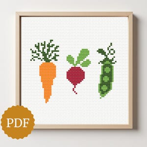 May include: Cross-stitch artwork featuring a carrot, radish, and pea pod. The carrot is orange with green tops, the radish is red with green leaves, and the pea pod is green. The artwork is framed in a light wood frame.