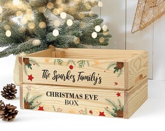 Op de afbeelding: Een houten kerst-avondbox met een feestelijk ontwerp. De doos is versierd met dennentakken, rode sterren en een rood ornament. De tekst "The Sparkes Family's Christmas Eve Box" is op de voorkant van de doos gedrukt.