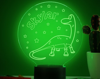 May include: A green night light with a dinosaur and stars design. The light is personalized with the name "Skylar".