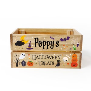 May include: A rectangular wooden crate featuring the text "Poppy's HALLOWEEN TREATS" in black lettering. The crate is decorated with colourful illustrations of a crescent moon, a witch hat, bats, a spider web, a ghost, a tombstone, a black cat, and pumpkins.