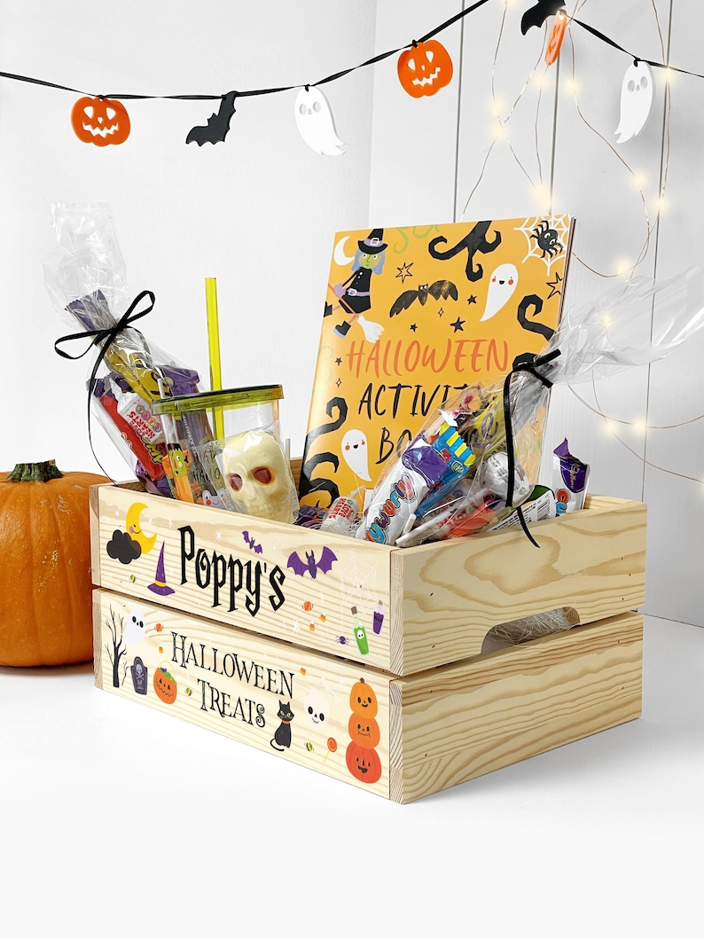 May include: A light-coloured wooden crate featuring the text Poppy's Halloween Treats and colourful holiday graphics. Inside are clear plastic bags filled with assorted sweets, a skull-shaped item, and a Halloween activity book.