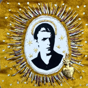 May include: A square gold velvet patch featuring a central white oval with a black and white portrait of David Bowie. The portrait is surrounded by a gold halo, embroidered rays in silver and purple thread, small gold stars, and a gold heart charm.