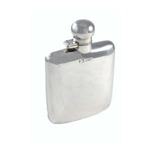 Puede incluir: Una petaca de color plateado con una parte superior redondeada y un pequeño tapón esférico. La petaca tiene un cuerpo rectangular con bordes ligeramente curvados. El tapón está sujeto con un mecanismo de bisagra. La petaca parece ser de metal.