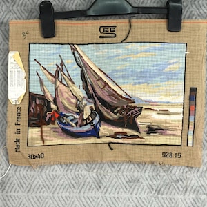 Puede incluir: Un tapiz de punto de aguja que representa veleros en una playa, con cielo azul y agua. La obra de arte está enmarcada con un borde marrón y está etiquetada como "Made in France". El tapiz mide 30 x 40 cm.
