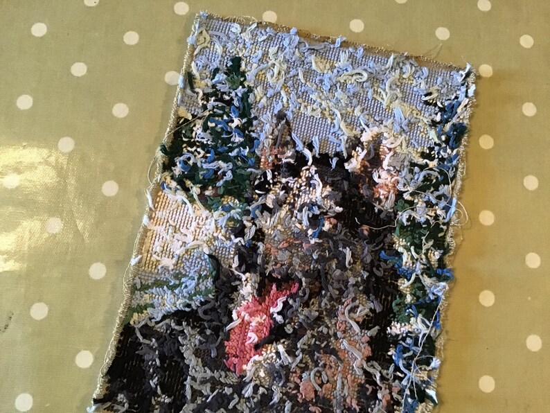May include: A rectangular textile art piece depicting a landscape scene with trees and a mountain. The artwork features a textured, raised surface with various colors, including green, blue, pink, and gray. The edges of the textile are frayed.