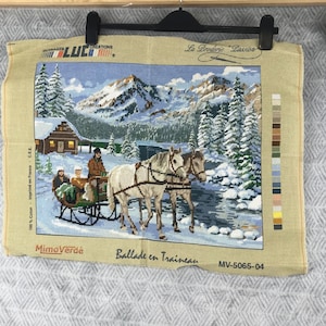 Puede incluir: Tapiz de punto de aguja que representa una escena invernal con un trineo tirado por caballos. La obra de arte representa un paisaje nevado con montañas, árboles y una cabaña. El tapiz incluye el texto "Ballade en Traineau" y "MimoVerdé".