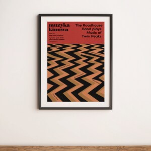 May include: A black framed poster with a red background and black and brown zig-zag pattern. The poster advertises a music event called "muzyka kinowa" featuring the Roadhouse Band playing music from the TV show Twin Peaks.
