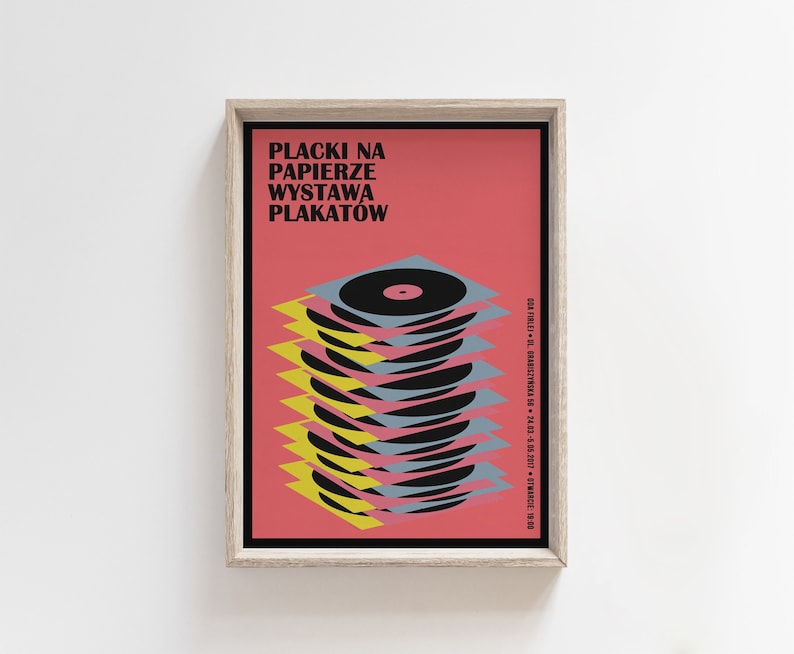 May include: A framed poster with a pink background and the text "Placki na Papierze Wystawa Plakatow". The poster features a stack of colourful vinyl records.