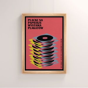 May include: A framed poster with a red background and the text "Placki na Papierze Wystawa Plakatow". The poster features a stack of black vinyl records with yellow and blue accents.