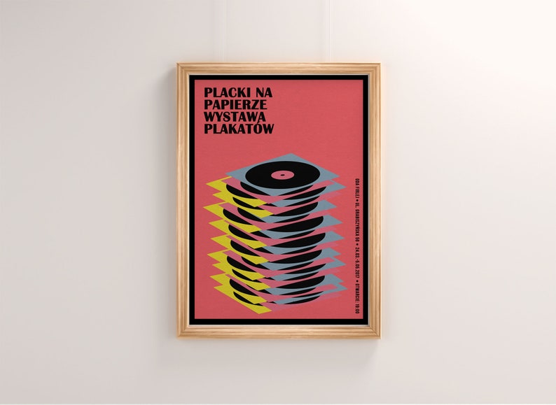 May include: A framed poster with a red background and the text "Placki na Papierze Wystawa Plakatow". The poster features a stack of black vinyl records with yellow and blue accents.
