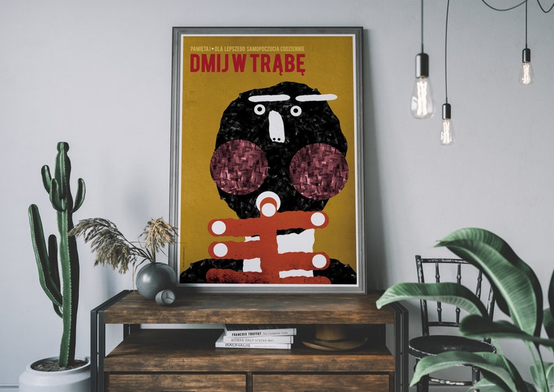 May include: A yellow and red poster with a black and white illustration of a person's face. The poster has the text "DMJW TRABĘ" in red letters.