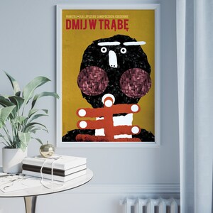 May include: A yellow and black poster with the text "DMJW TRABE" in red. The poster features a cartoon illustration of a person with a black head and red cheeks.