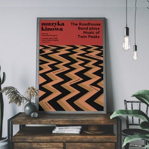 May include: A red and black poster with the text "muzyka kinowa" and "The Roadhouse Band plays Music of Twin Peaks". The poster features a black and brown zig-zag pattern with the names of the show's characters.