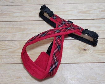 May include: Red and black plaid dog harness with a fleece lining. The harness has two adjustable straps with black buckles.