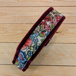 K&ouml;nnte beinhalten: Ein burgunderfarbenes Samthalsband mit einem floralen Stoffeinsatz. Das Halsband ist mit einem bunten Blumenmuster in Rot-, Blau-, Gr&uuml;n- und Gelbt&ouml;nen verziert.