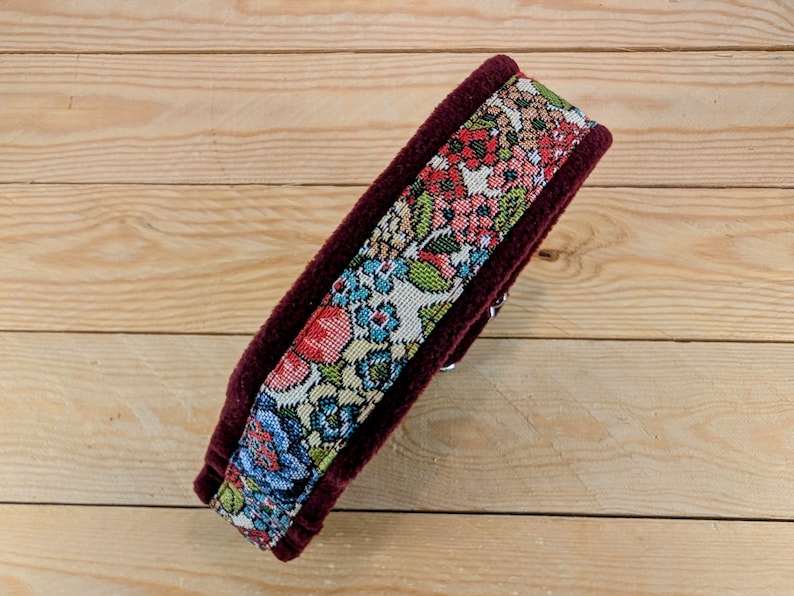 K&ouml;nnte beinhalten: Ein burgunderfarbenes Samthalsband mit einem floralen Stoffeinsatz. Das Halsband ist mit einem bunten Blumenmuster in Rot-, Blau-, Gr&uuml;n- und Gelbt&ouml;nen verziert.