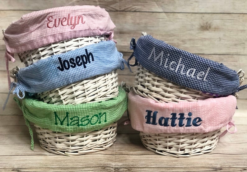 Pu&ograve; includere: Quattro cesti di vimini bianchi con fodere in tessuto. Le fodere sono rosa, blu, verde e vichy blu e bianco. Ogni fodera ha un nome ricamato: Evelyn, Joseph, Mason e Hattie.