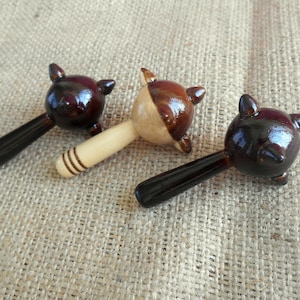 May include: Three wooden rattles with brown and black painted animal heads. The rattles have wooden handles.
