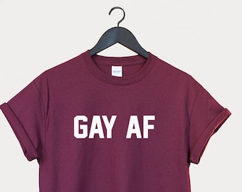 May include: A maroon t-shirt with the text "GAY AF" printed in white on the front.