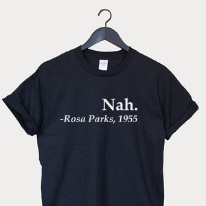 Peut inclure: T-shirt noir avec un texte blanc qui dit "Nah. -Rosa Parks, 1955"