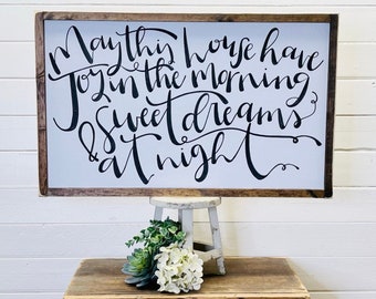 May include: A white wooden sign with black calligraphy that reads "May this house have joy in the morning & sweet dreams at night".