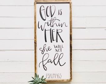 May include: A wooden sign with a white background and black calligraphy that reads "God is within her, she will not fall, Psalm 146:5".