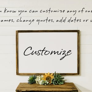 May include: A white wooden sign with the word "Customize" written in black cursive script. The sign is hanging on a white wall with wood paneling. The text above the sign reads "Did you know you can customize any of our signs?! Add names, change quotes, add dates or words".