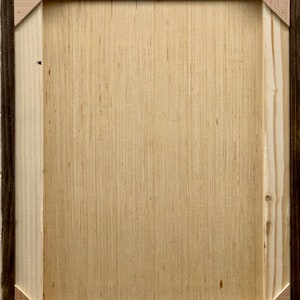 May include: A wooden frame with a light brown wood surface. The frame has a dark brown outer edge and a light brown inner edge.