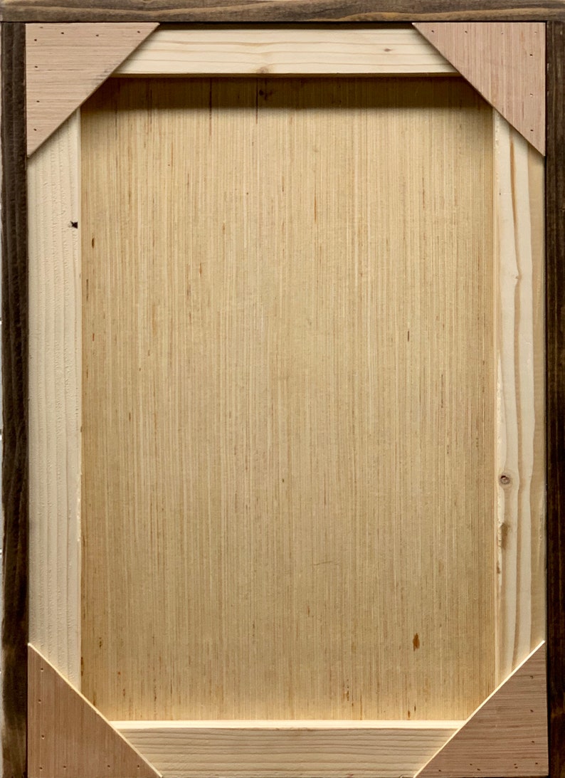May include: A wooden frame with a light brown wood surface. The frame has a dark brown outer edge and a light brown inner edge.