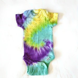 Könnte beinhalten: Ein tie-dye Baby-Body mit einem Spiralmuster in Gelb-, Grün-, Blau- und Violetttönen. Der Body hat einen kleinen Sternendruck über die gesamte Fläche.