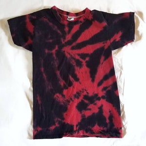 K&ouml;nnte beinhalten: Ein rot-schwarzes Batik-T-Shirt mit einem Wirbelmuster.