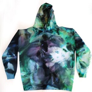 May include: A tie-dye hoodie in shades of blue, green, and purple. The hooded sweatshirt has a front pocket and ribbed cuffs and hem. The dye pattern creates a marbled effect across the fabric.