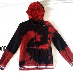 Puede incluir: Sudadera con capucha roja y negra tie-dye con cremallera y rayas blancas en los pu&ntilde;os y la cintura. "FRONT" est&aacute; escrito en negro en la esquina inferior izquierda de la imagen.