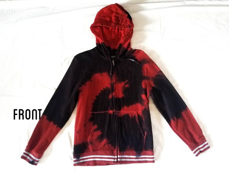 Puede incluir: Sudadera con capucha roja y negra tie-dye con cremallera y rayas blancas en los pu&ntilde;os y la cintura. "FRONT" est&aacute; escrito en negro en la esquina inferior izquierda de la imagen.