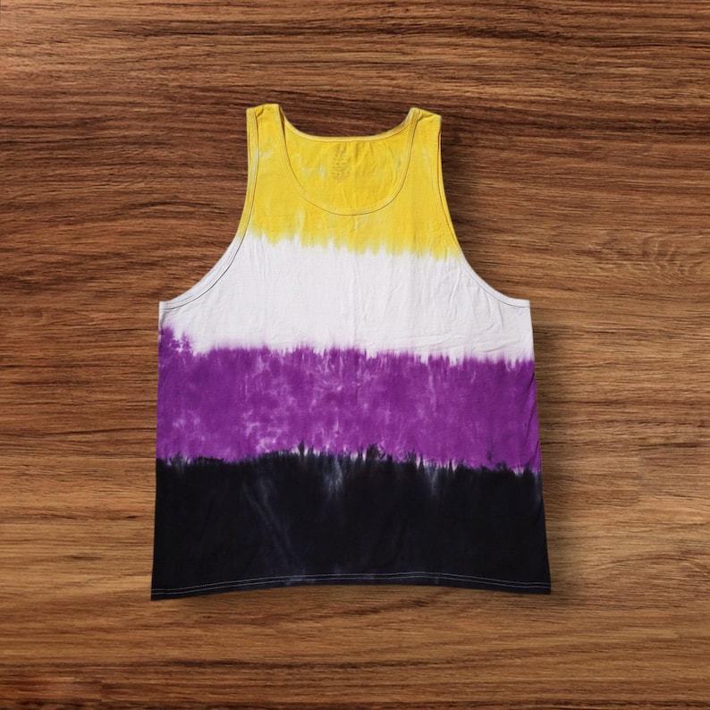 May include: A sleeveless tank top with a tie-dye design. The top features horizontal bands of yellow, white, purple, and black. The garment is made of a soft material and is suitable for casual wear.