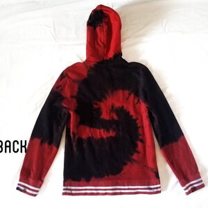 Puede incluir: Sudadera con capucha de color rojo y negro tie-dye con rayas blancas en los pu&ntilde;os y la cintura. La sudadera tiene una capucha con cord&oacute;n.