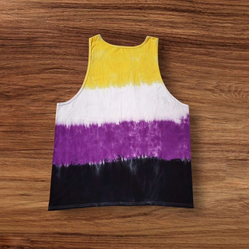 May include: A sleeveless tank top with a tie-dye design in yellow, white, purple, and black. The top is made of a soft fabric and has a scoop neck. The colors are arranged in horizontal bands.
