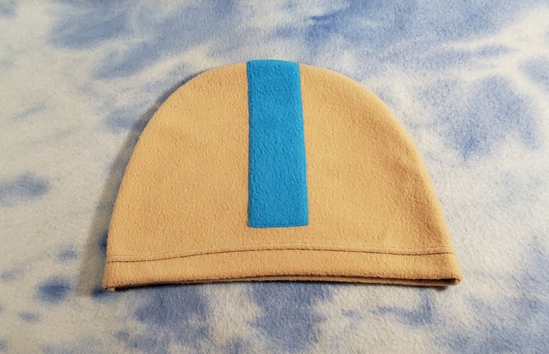 May include: A beige fleece beanie with a blue stripe down the center.