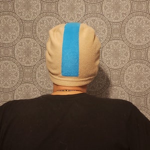 May include: A beige fleece beanie with a blue stripe down the center.