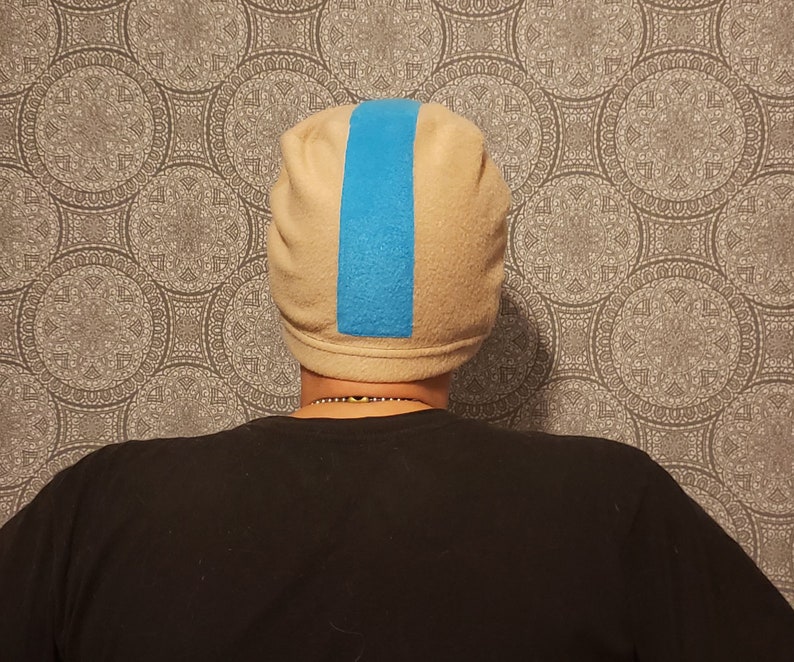 May include: A beige fleece beanie with a blue stripe down the center.