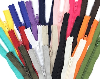 May include: A collection of different colored zippers, including black, white, red, orange, yellow, green, blue, and pink. The zippers are arranged in a fan shape and are all closed.