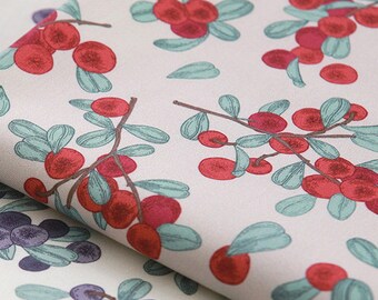 May include: A white fabric with a repeating pattern of red berries and green leaves. The fabric is folded in half, showing the pattern on both sides.