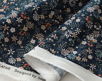 May include: A navy blue fabric with a small white, pink, and blue floral print. The fabric is folded and the edge is visible. The text "Designed by heajiu" is visible on the fabric.