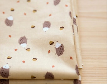 Può includere: Tessuto beige con un motivo ripetitivo di ricci marroni che portano ghiande. Il tessuto è piegato in tre.