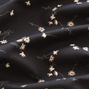 May include: Black fabric with a white and brown floral pattern. The fabric is soft and has a subtle sheen.