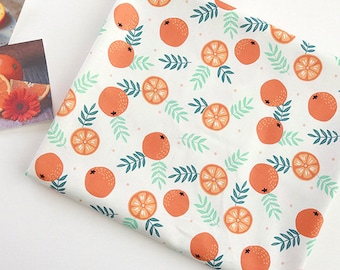 May include: White fabric with a repeating pattern of orange slices and green leaves. The fabric has a subtle white polka dot pattern.