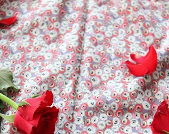 May include: A single red rose with green leaves on a fabric background with a repeating pattern of small red and white circles.